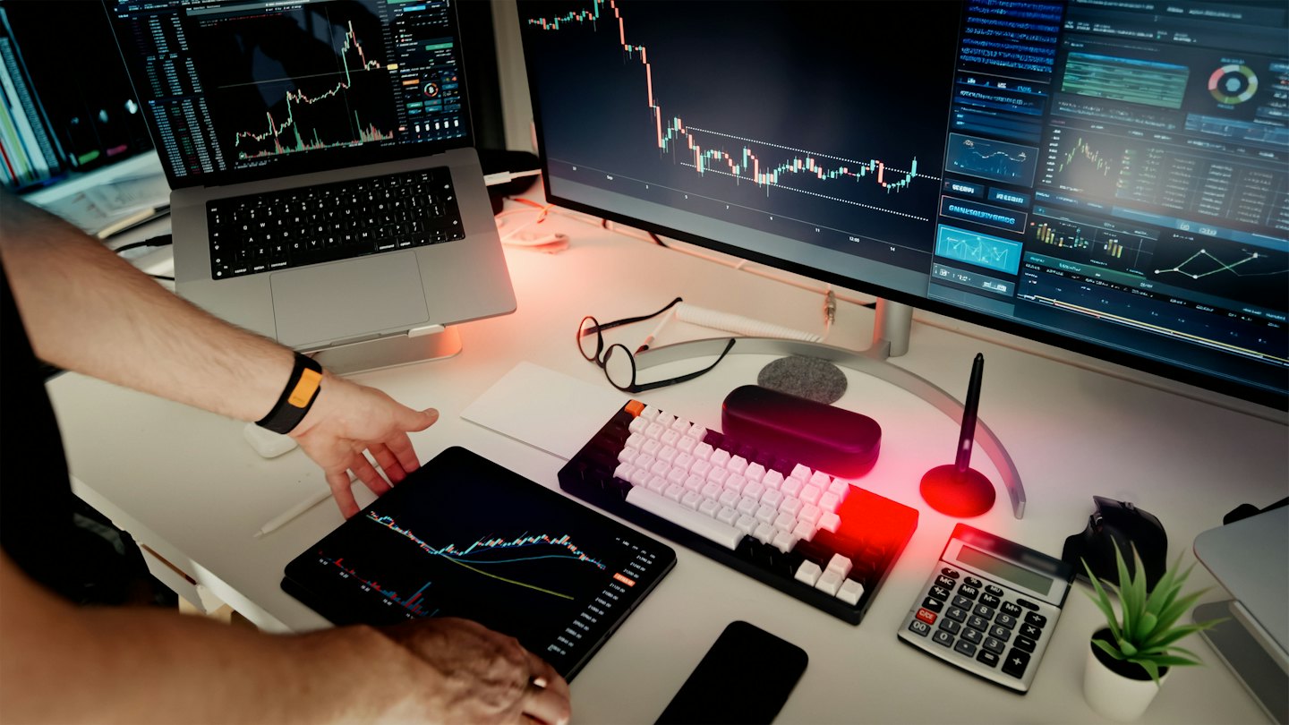 Hands using a tablet with financial charts in a modern office.